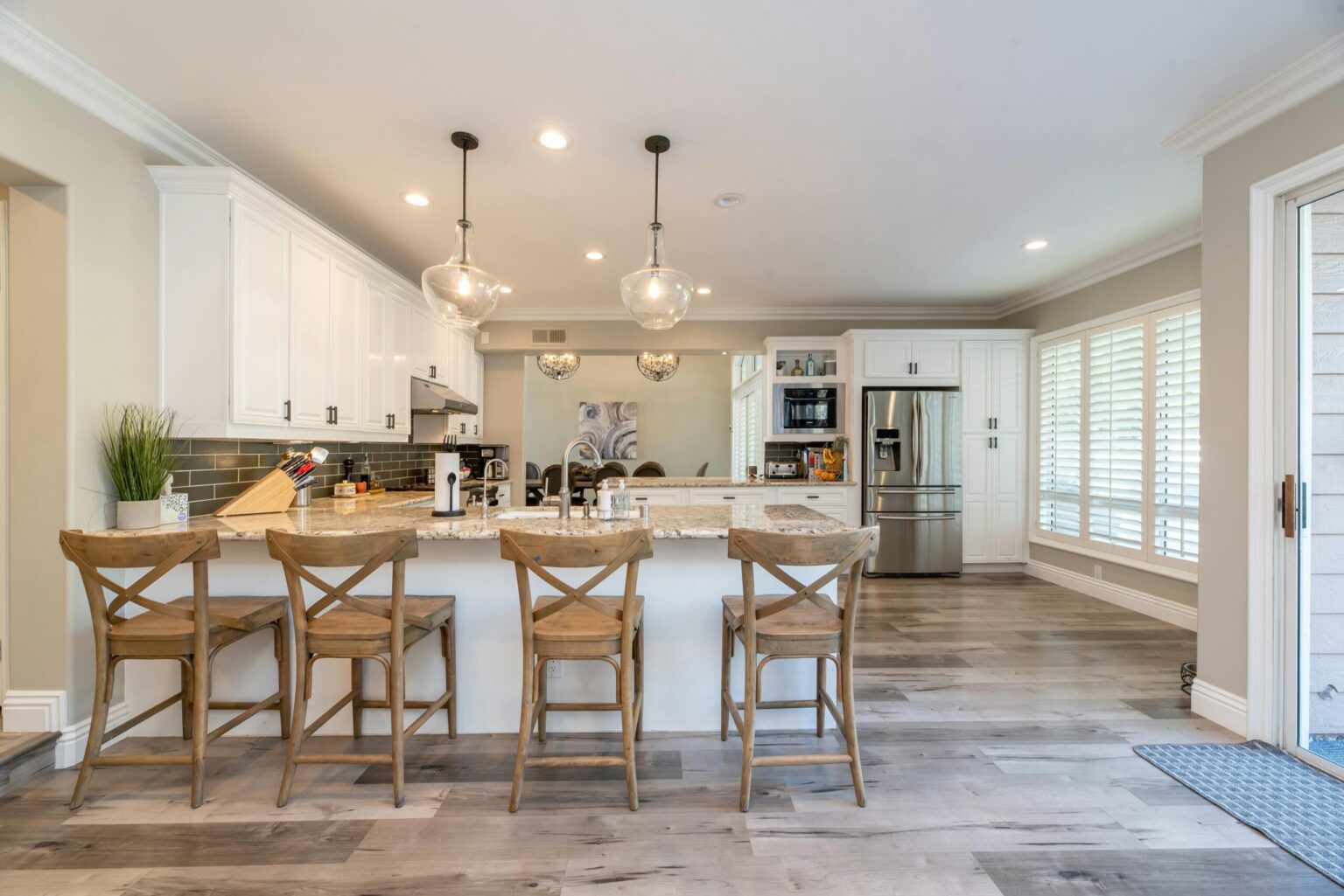 Bright modern kitchen with white cabinets and wooden bar stools.